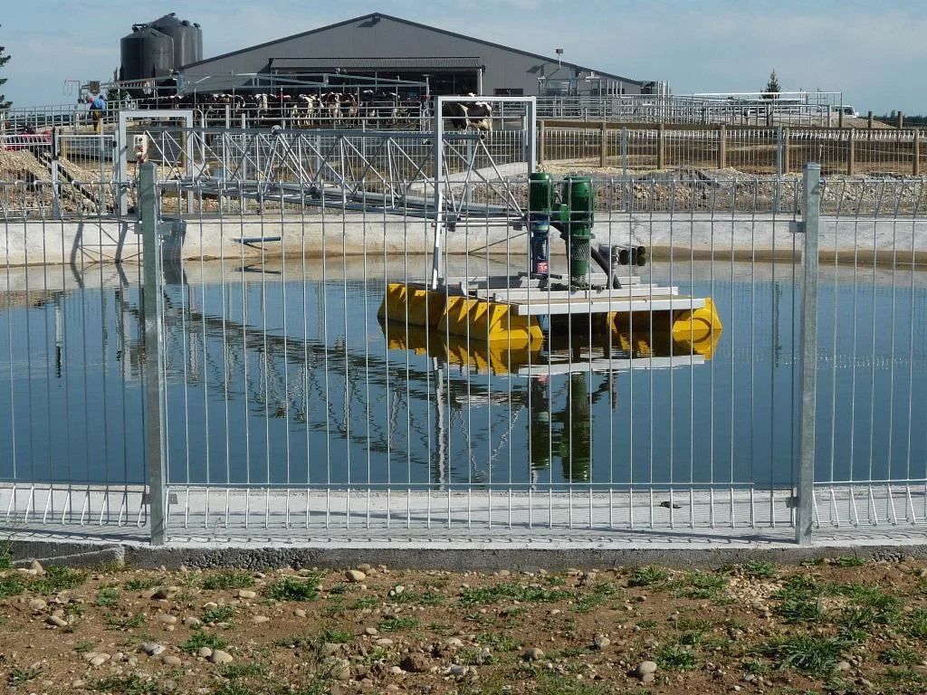 Floating pump pontoon on yellow pods in a fenced treatment pond